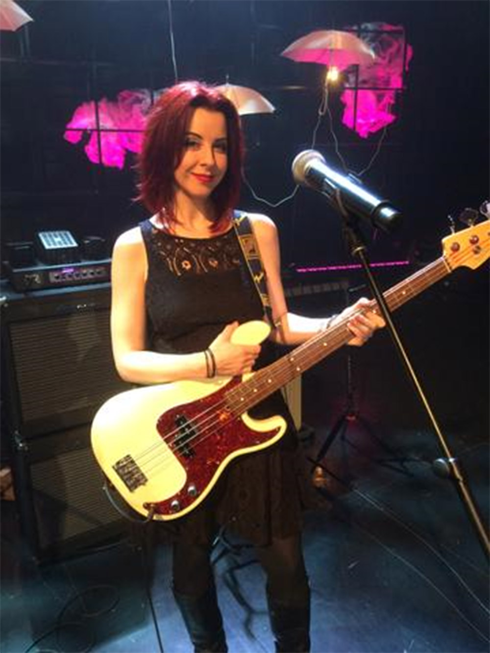 Jenn Oberle standing on stage holding a bass
