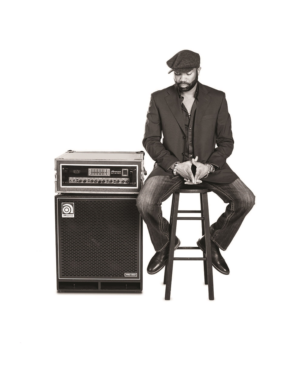 Pablo Stennett sitting on a stool by an Ampeg stack