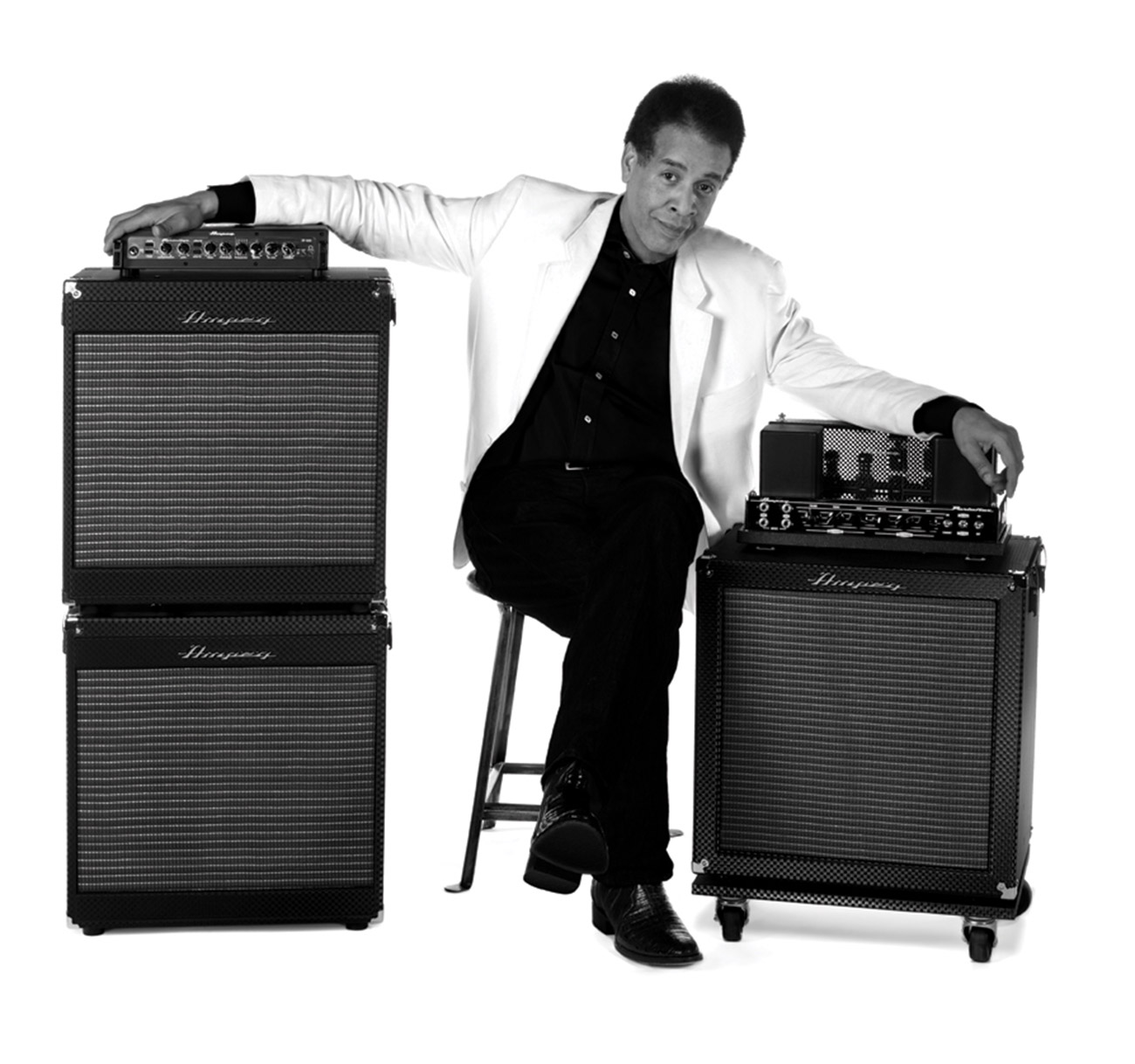 Stanley Clarke sitting between Ampeg cabs and heads