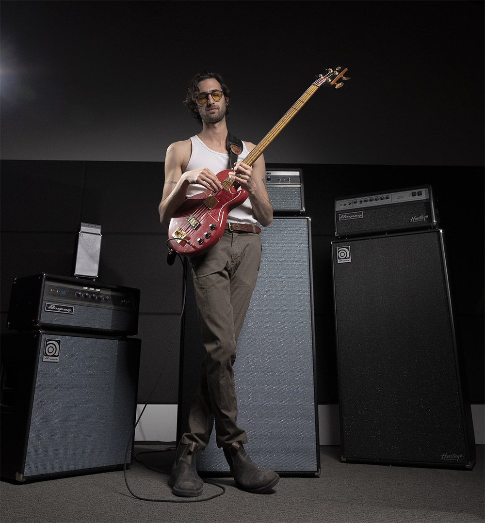 Wylie Gelber holding his bass in front of an Ampeg stack
