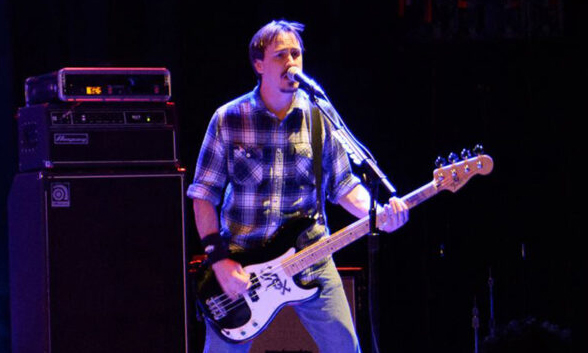 Ryan Manna on stage playing bass in front of Ampeg stack