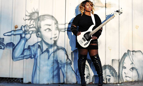 Bassist Téja Veal standing in front of street art