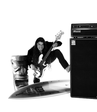 Robert Trujillo standing by a tiki statue holding a bass with his leg over a surfboard and foot on SVT-810E
