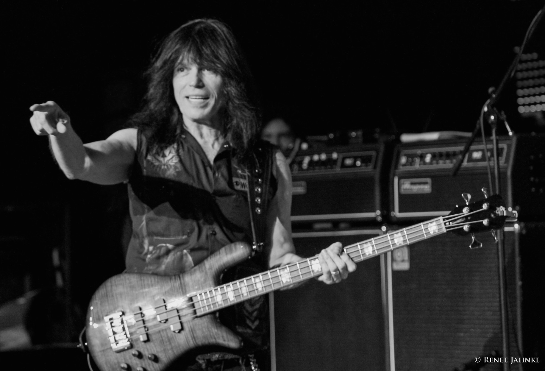 Rudy Sarzo holding a bass on stage pointing to the audience