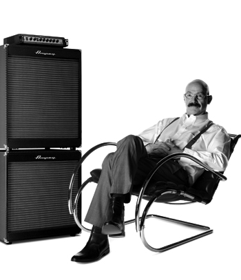 Tony Levin sitting in a chair next to an Ampeg stack