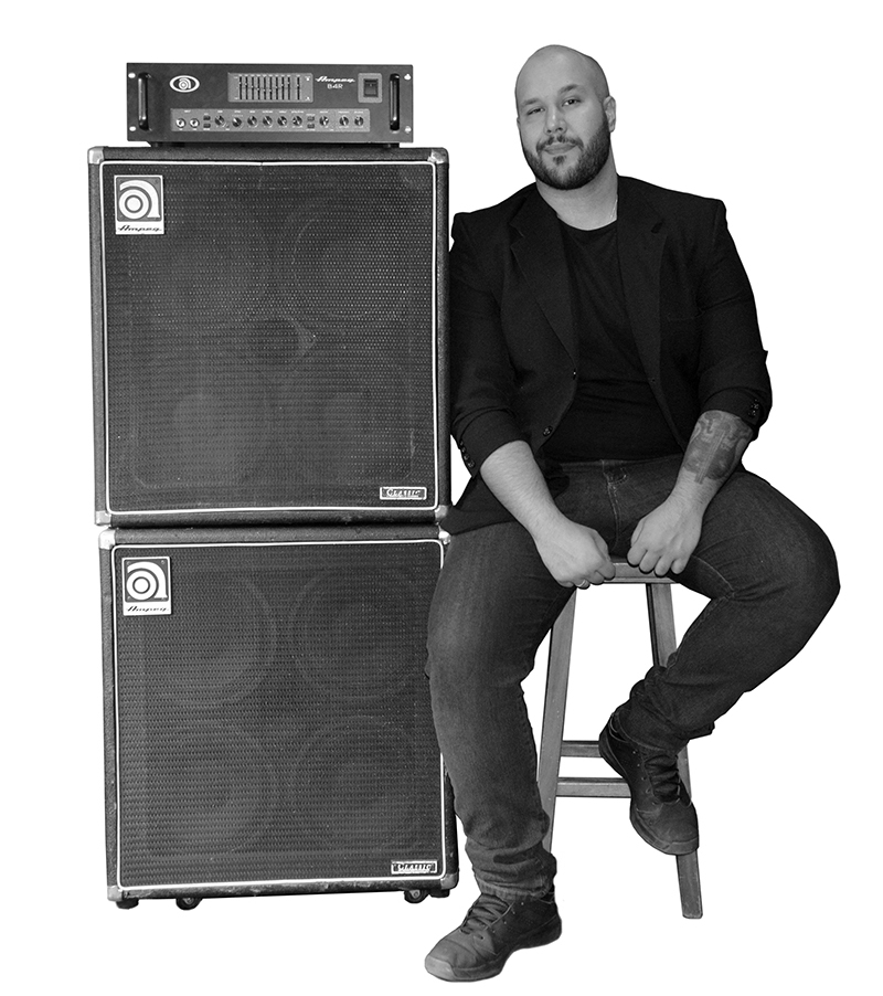 Bernardo Gosaric sitting on a stool leaning against stacked Ampeg Cabs