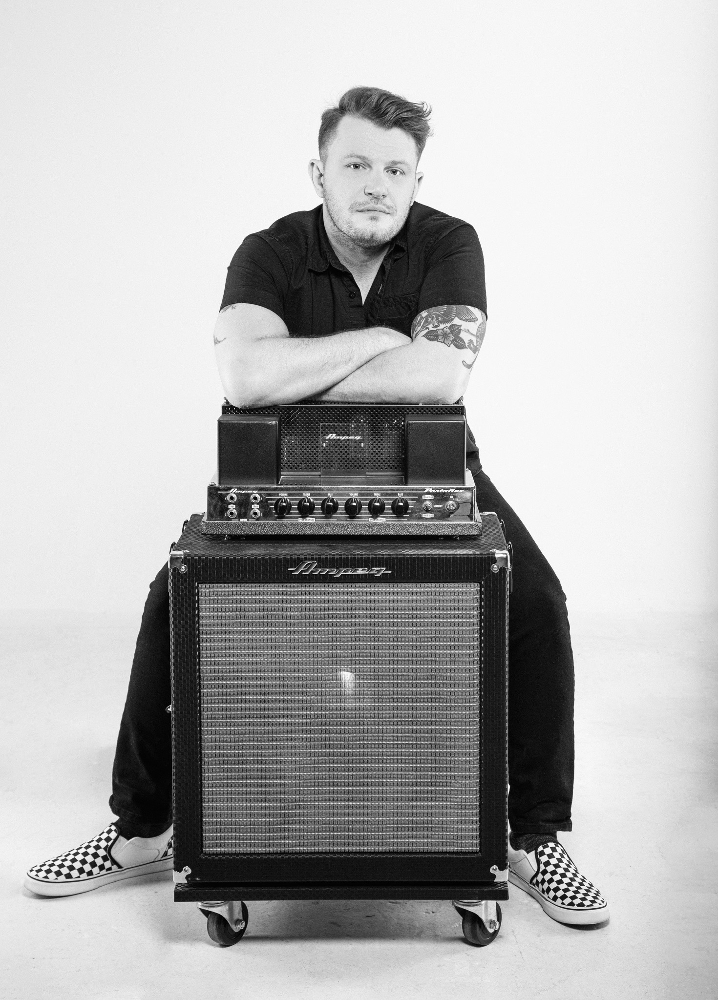 Shawn Scruggs sitting behind and leaning on an Ampeg head and cab