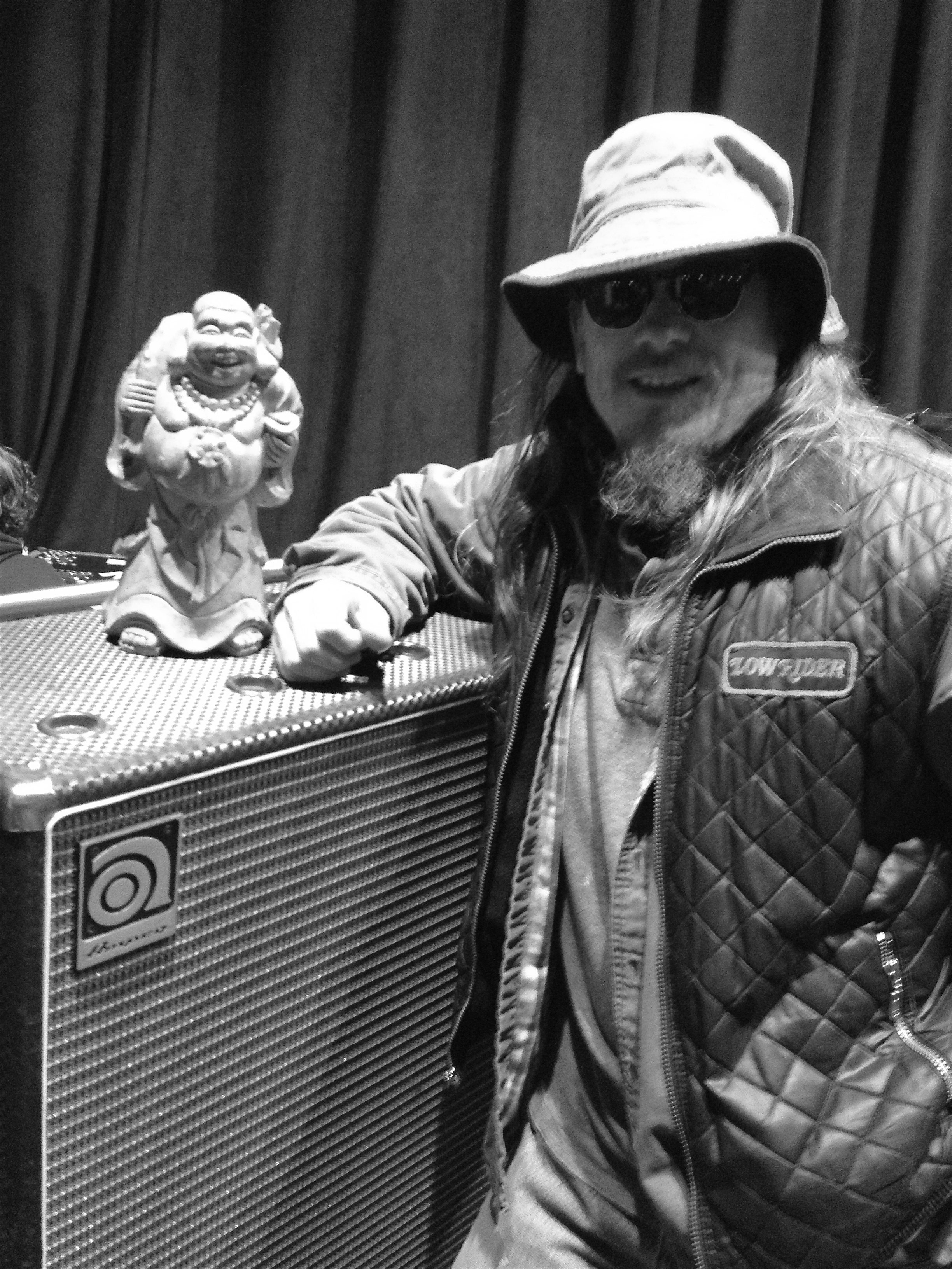 Jimi Prescott leaning on an Ampeg cab with a standing Buddha statue on top